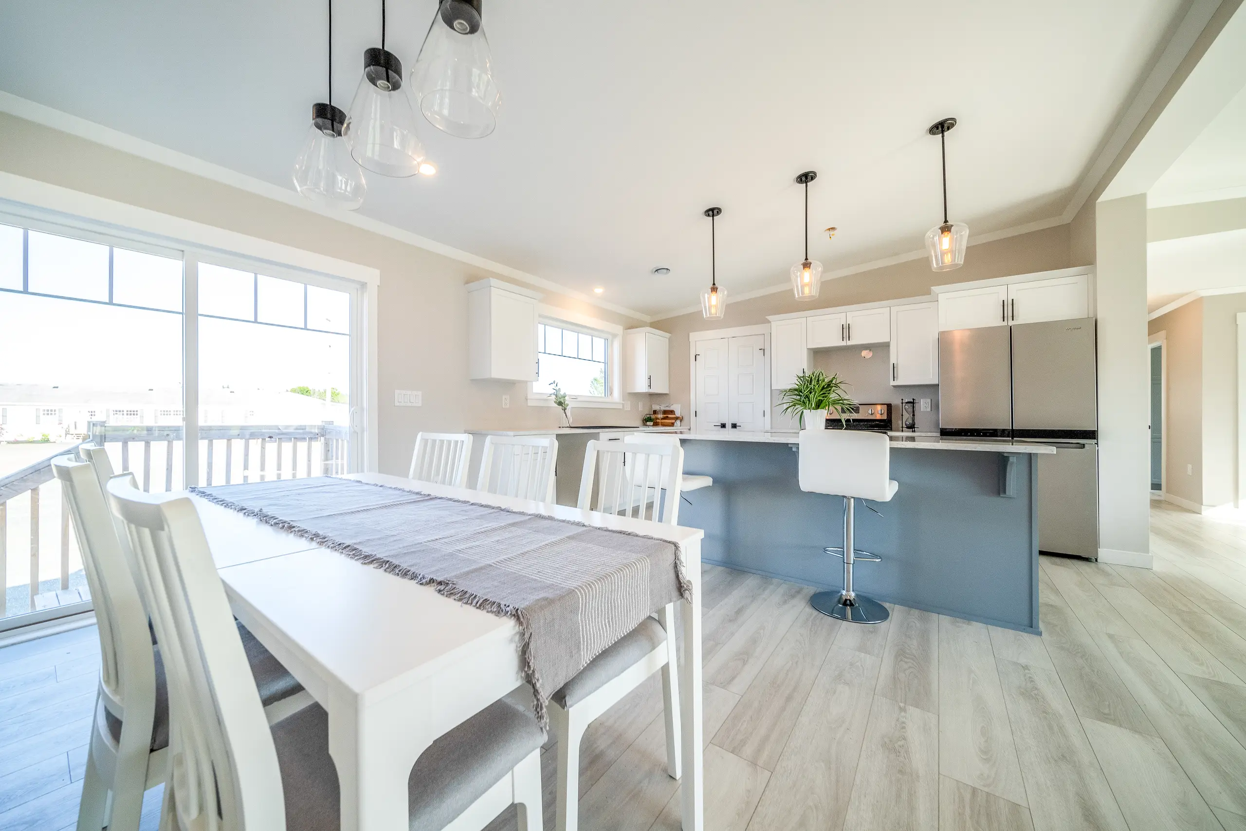 Open dining and kitchen space with a large island, pendant lighting, white cabinetry, and patio door access. 