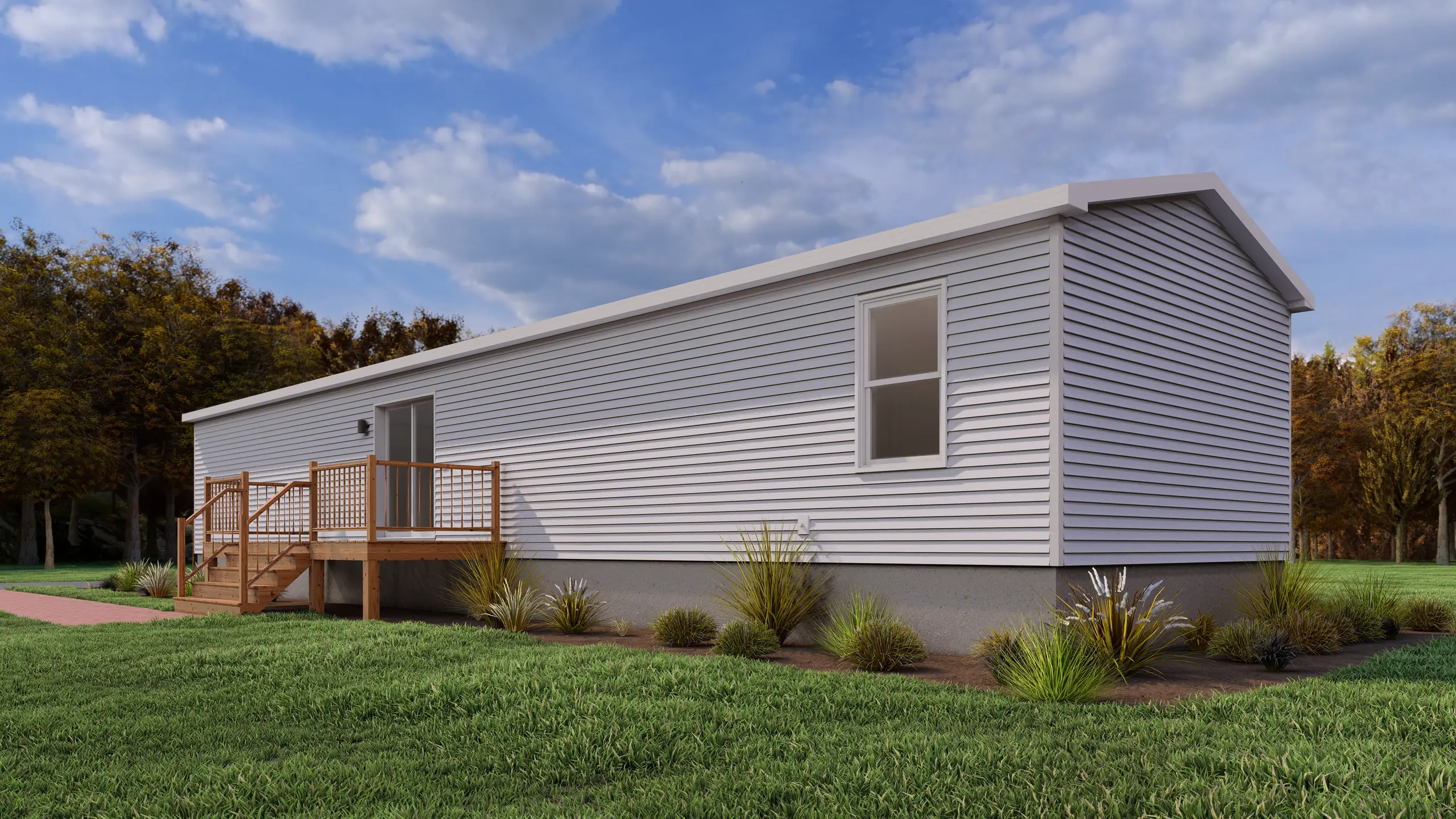 Rear corner view of a mini home featuring light grey siding, a raised wood deck with patio door access, and low-maintenance landscaping. 