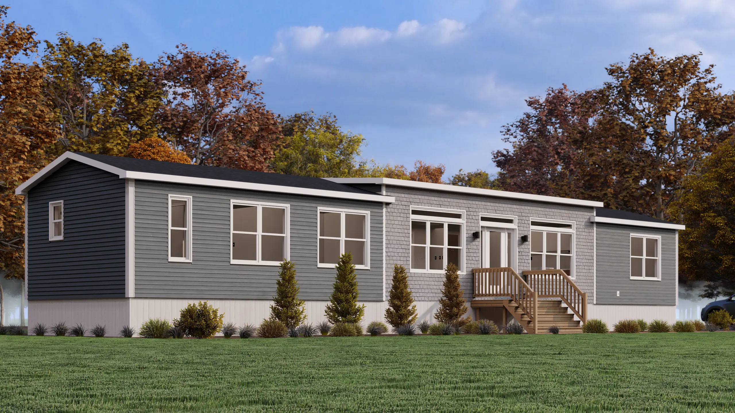 Side view of a modern modular home with light grey siding, a raised entry deck, narrow horizontal windows, and landscaped surroundings. 