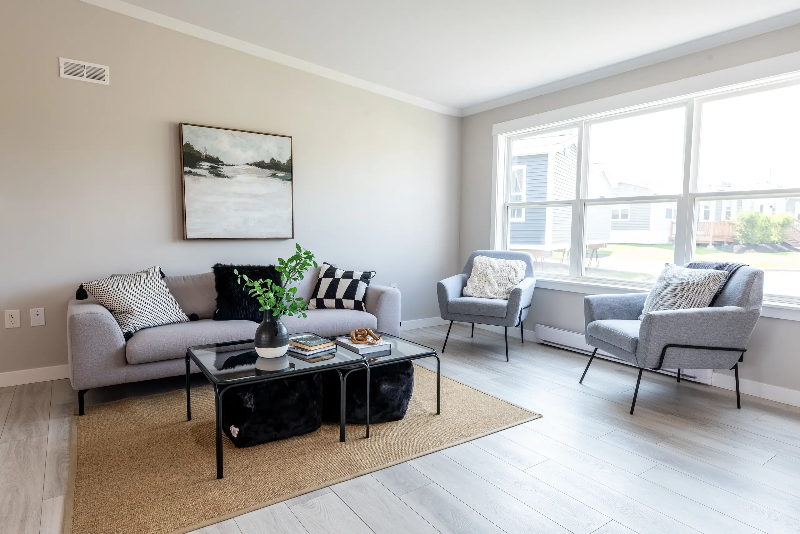 Open-concept living room with large windows, a contemporary sofa, accent chairs, and a glass coffee table.