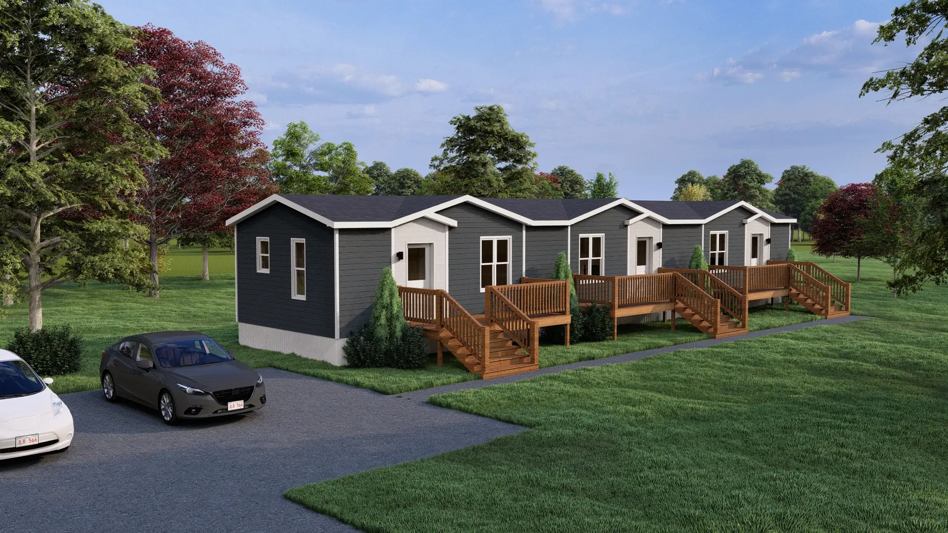 Side elevation of a contemporary multi-unit residential building with dark grey siding, multiple windows, landscaped perimeter plantings, and a low-maintenance exterior. 