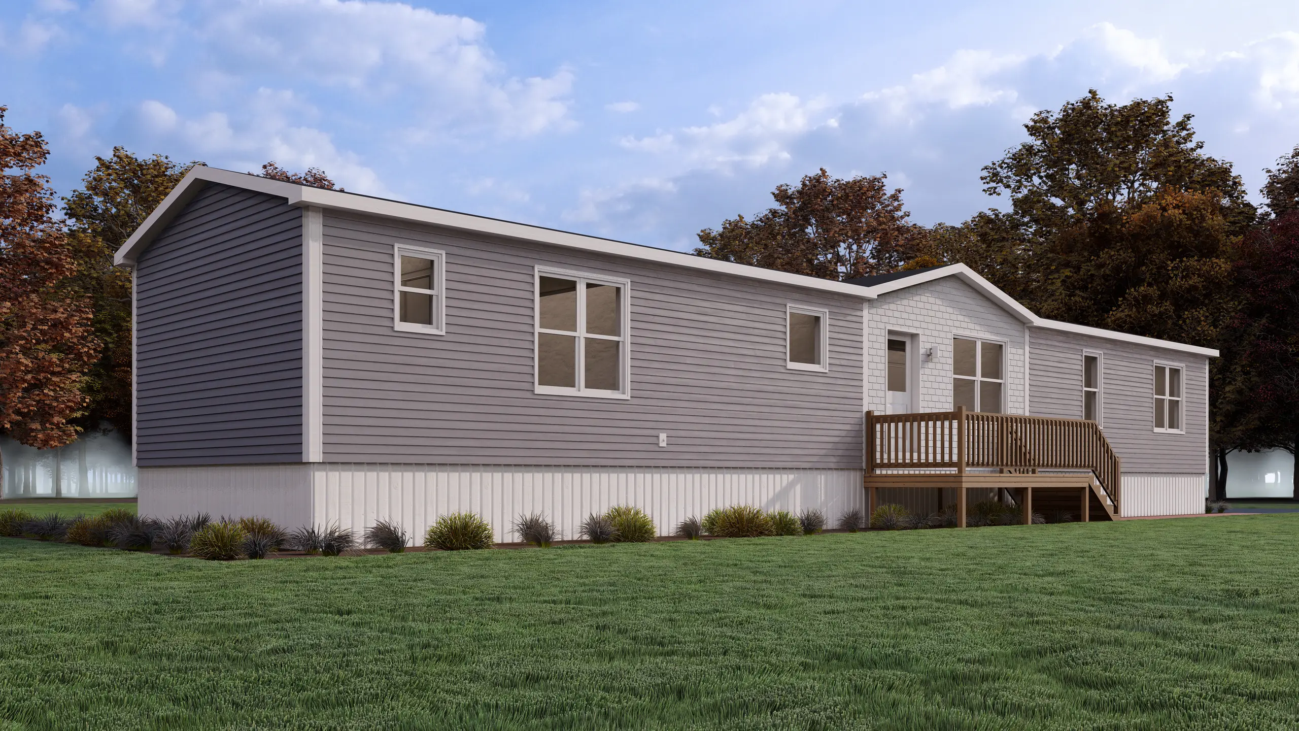 Front angled view of a contemporary mini home featuring grey siding, a white shingle accent façade, central entry deck, and landscaped foundation plantings. 
