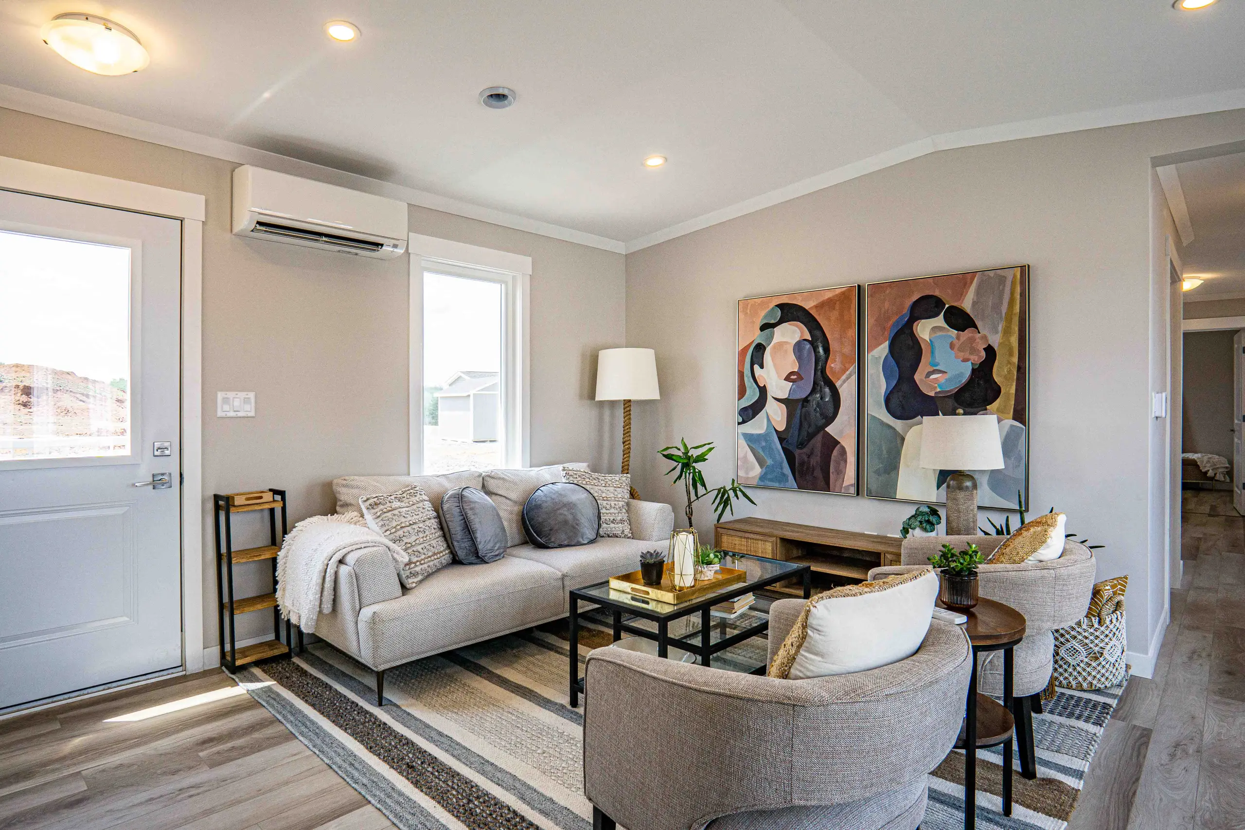 Open-concept living room with large windows, neutral finishes, comfortable seating, and modern décor throughout. 