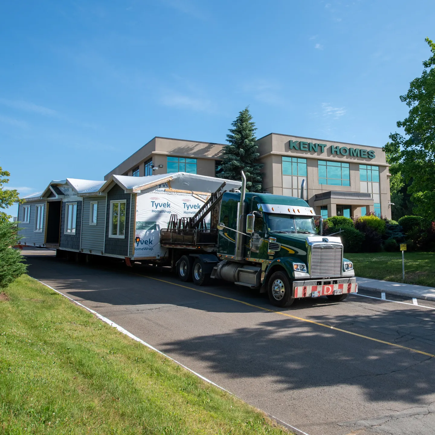 Modular home leaving the Kent Homes plant on a transport truck, highlighting the modular building process.