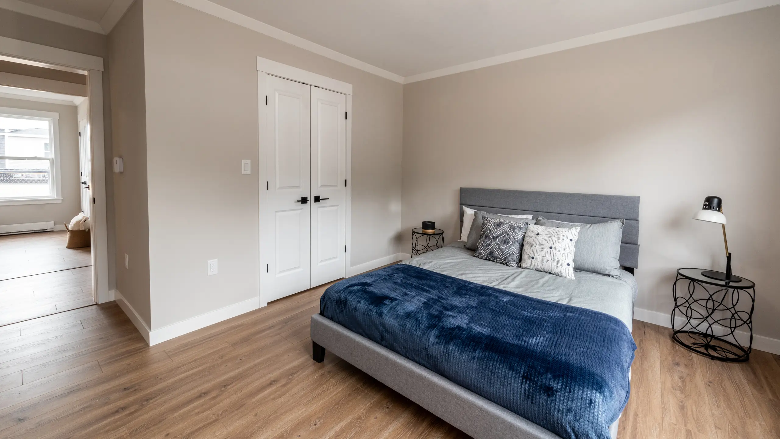 Primary bedroom with a queen bed, neutral décor, bedside tables, and a closet with double doors. 
