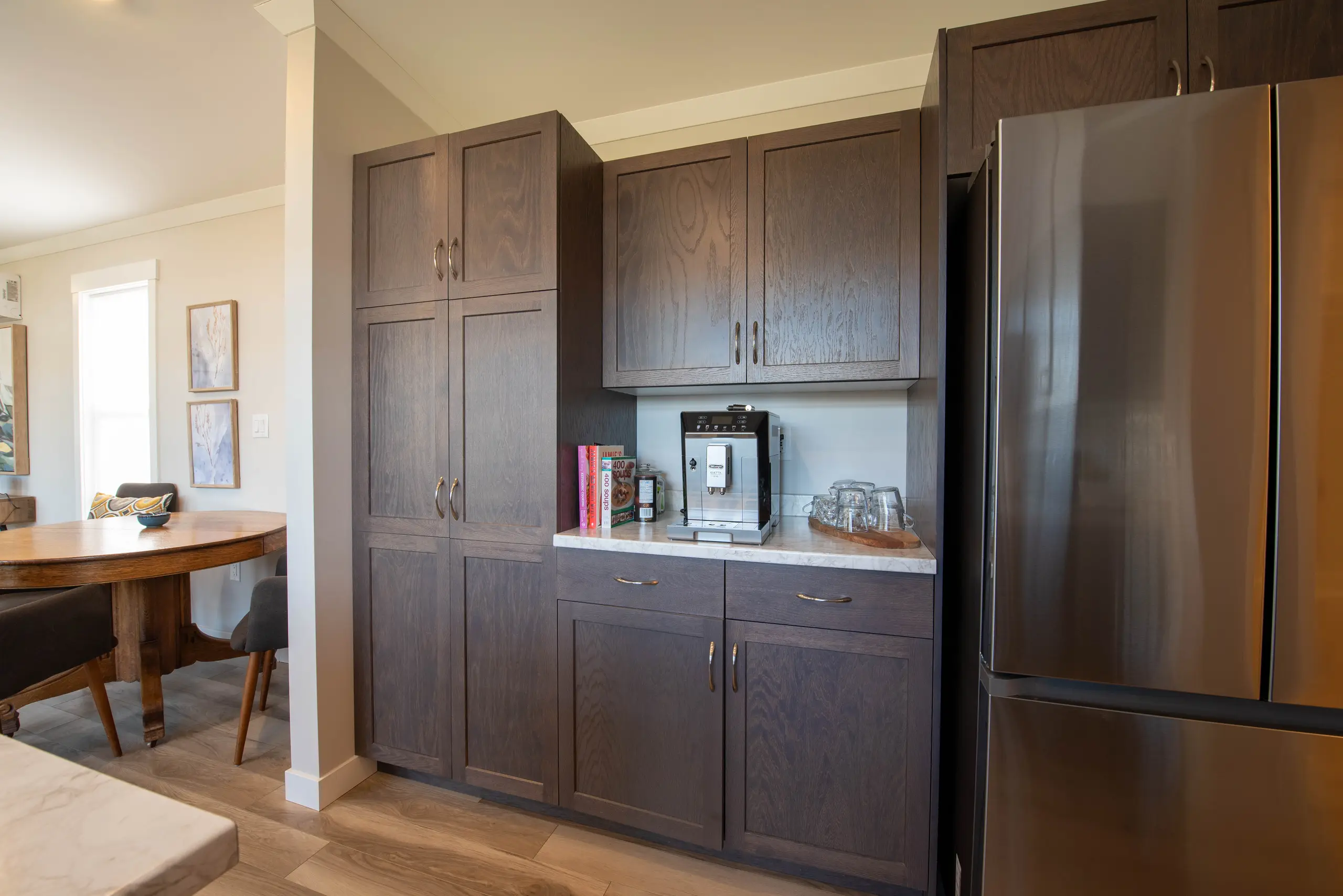 Kitchen pantry area featuring floor-to-ceiling dark wood cabinetry, a coffee station, and stainless steel refrigerator. 