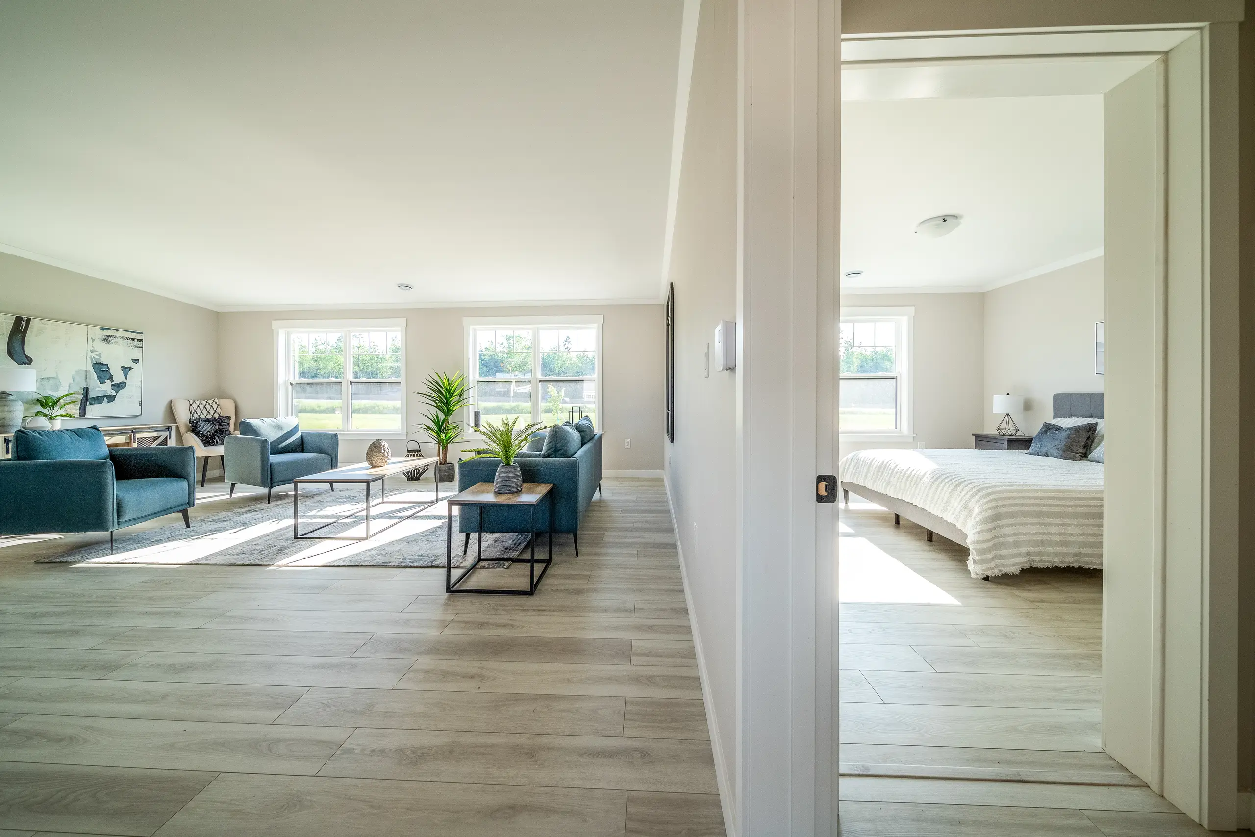 View from the hallway into a spacious open-concept living room with modern seating, large windows, and natural light. 
