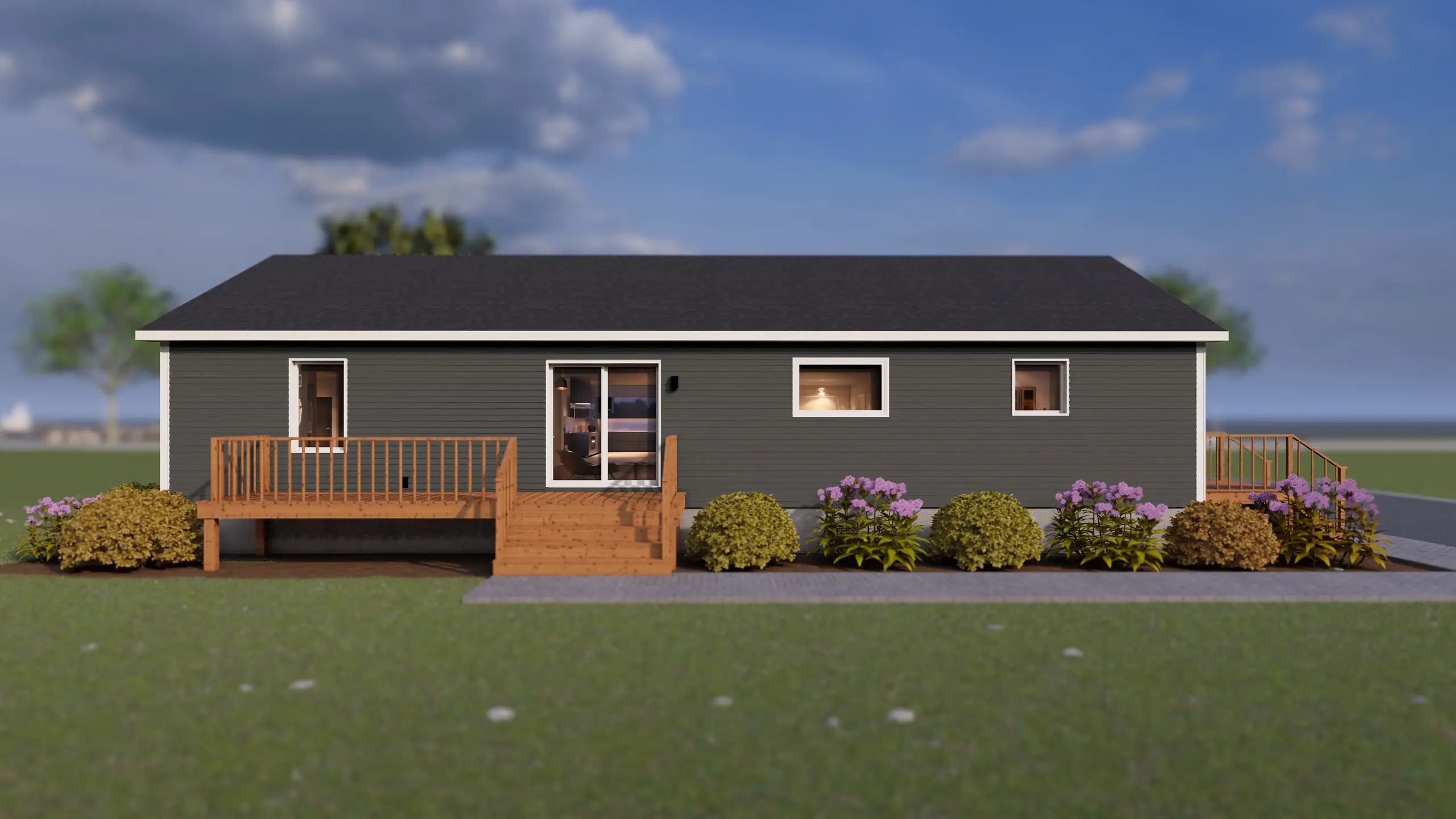 Rear view of a contemporary bungalow featuring a spacious raised deck, sliding patio doors, dark grey siding, and landscaped flower beds along the back of the home. 