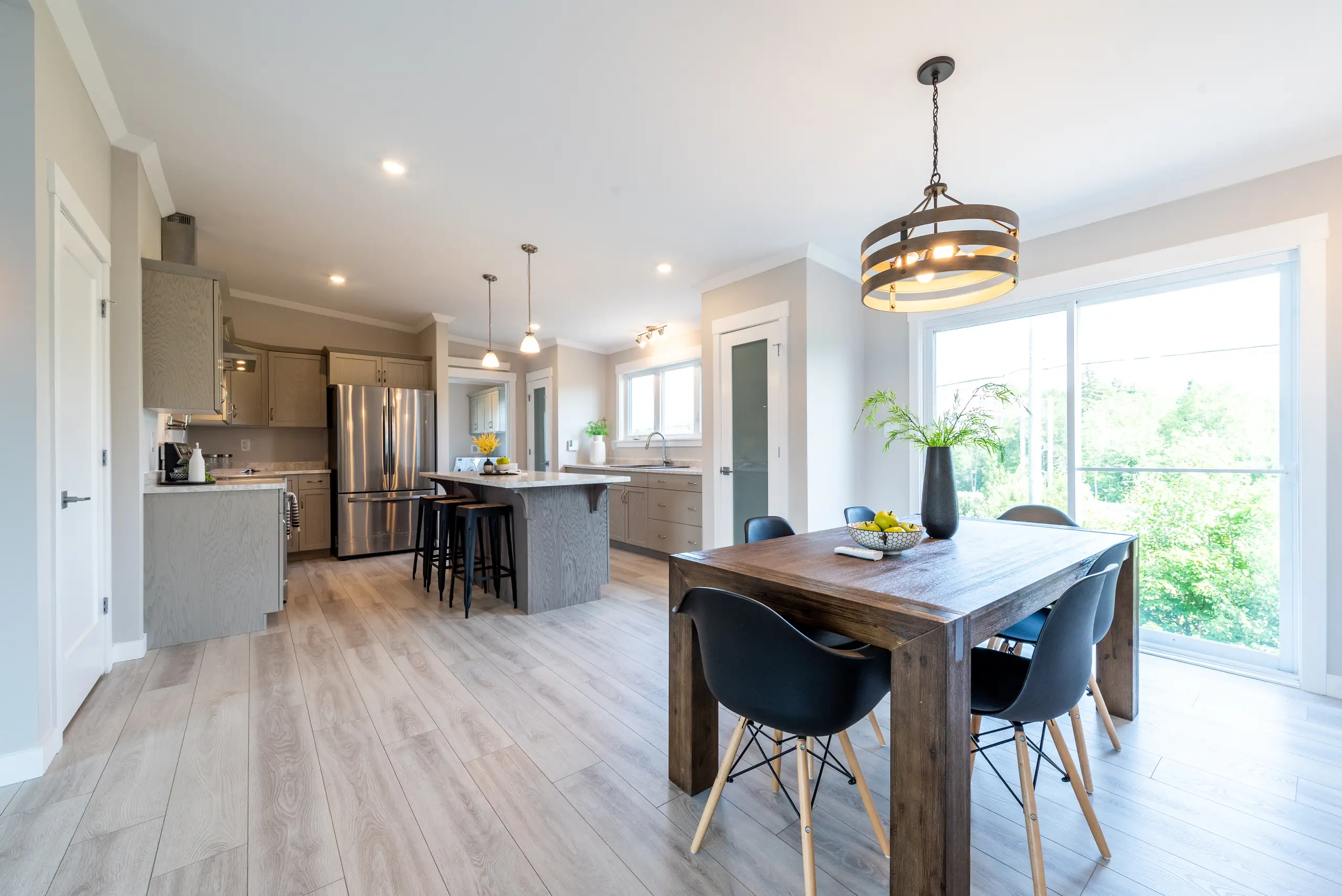 Spacious kitchen and dining area with a central island, modern cabinetry, stainless steel appliances, and large patio doors.