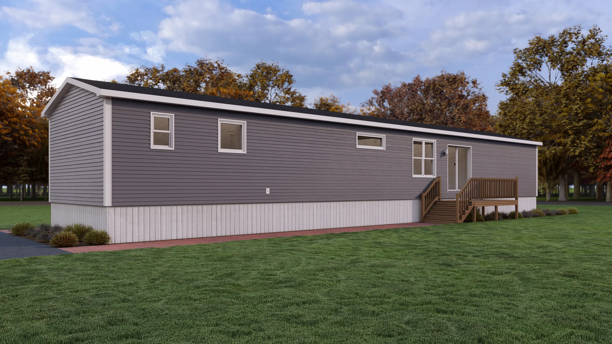 Side view of a modern mini home with grey siding, rear entry deck, horizontal accent window, and low-maintenance landscaping. 