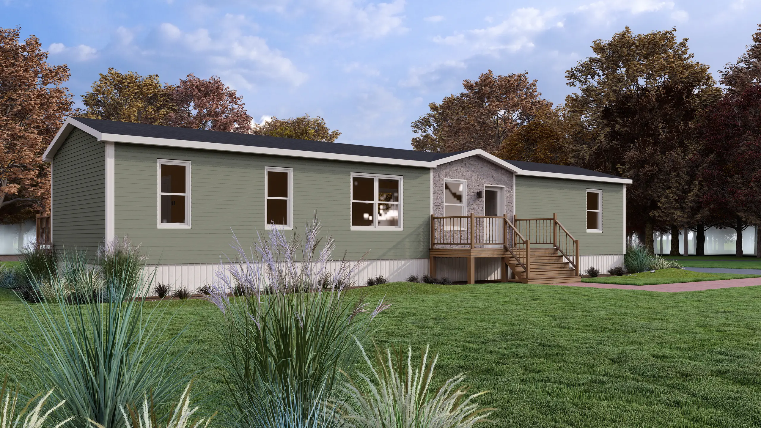 Front angled view of a contemporary mini home featuring sage green siding, a stone-accented central entrance, wood entry deck, and landscaped ornamental grasses. 