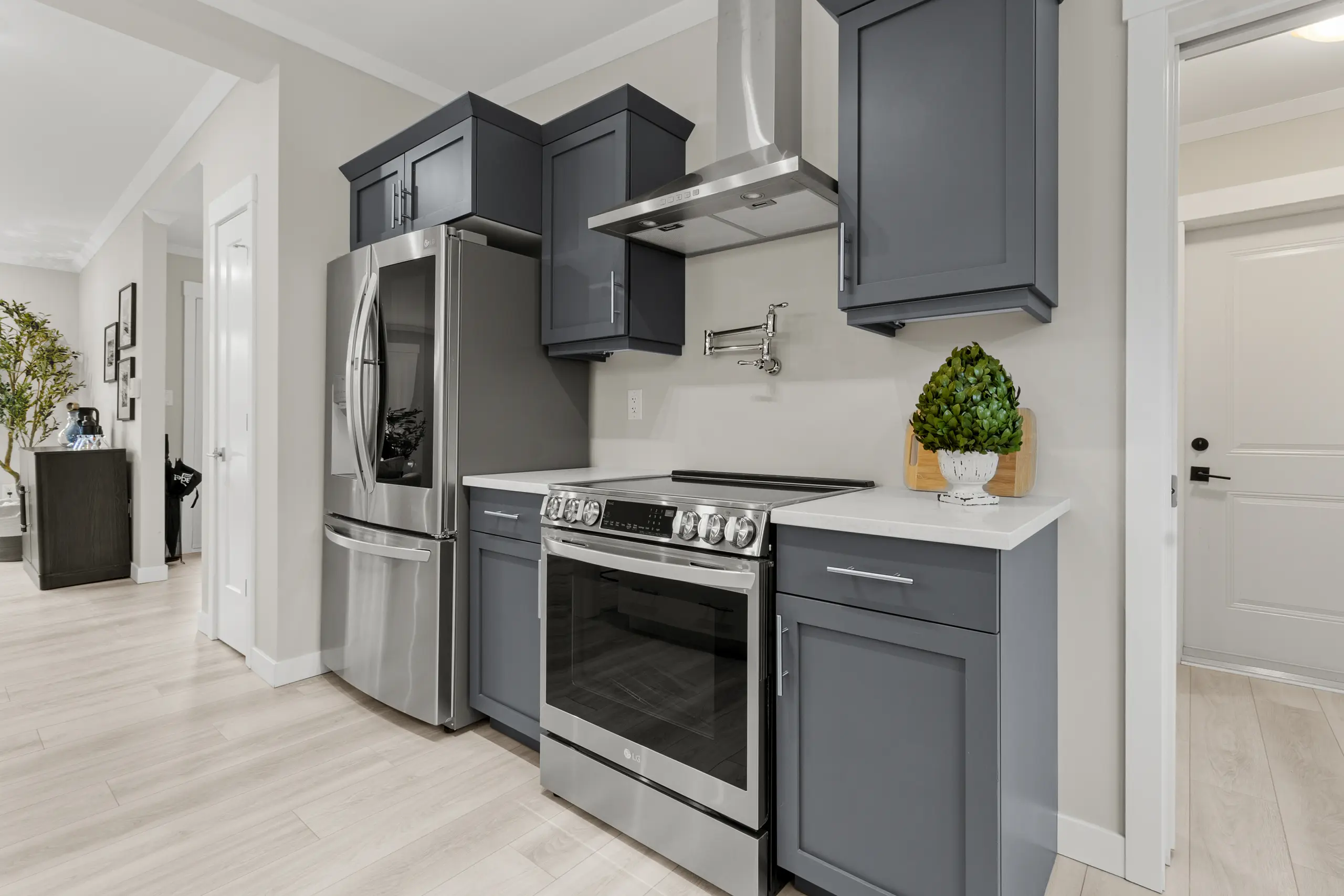 Contemporary kitchen with stainless steel range, grey cabinetry, white countertops, and modern finishes. 