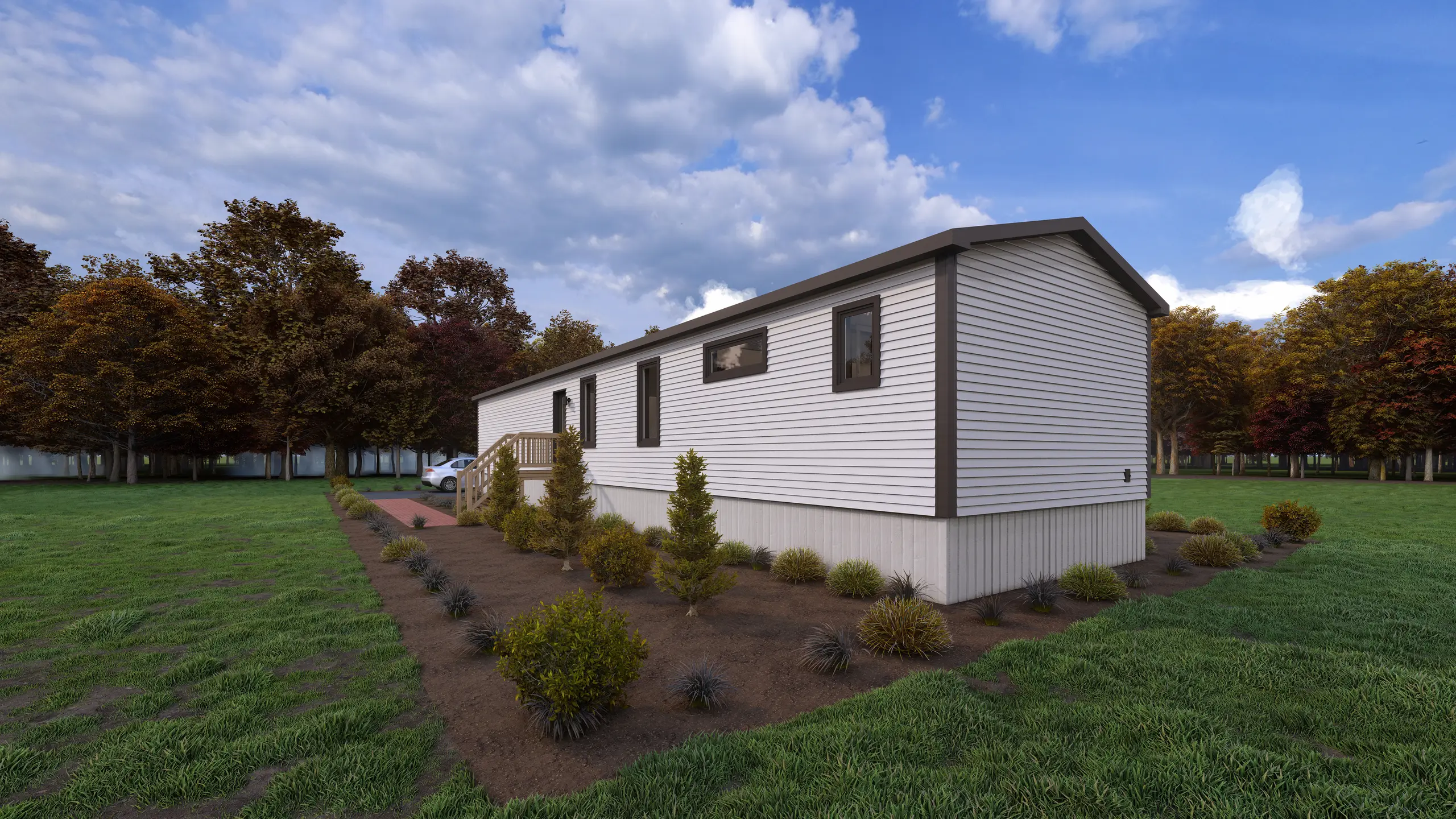 Rear corner view of a modern mini home with white siding, dark trim, side entrance deck, and landscaped grounds bordered by mature trees. 