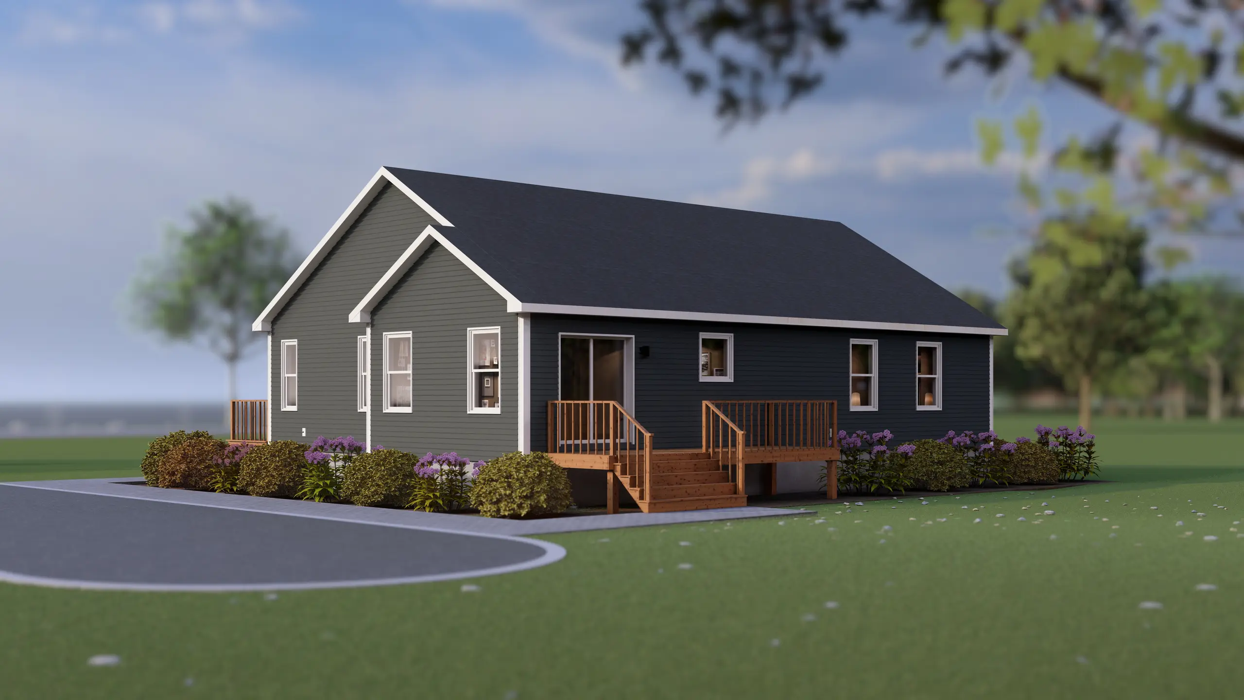 Angled rear view of a single-storey modular home with grey siding, a wooden deck with stairs, multiple windows, and surrounding landscaping including shrubs and flowering plants. 