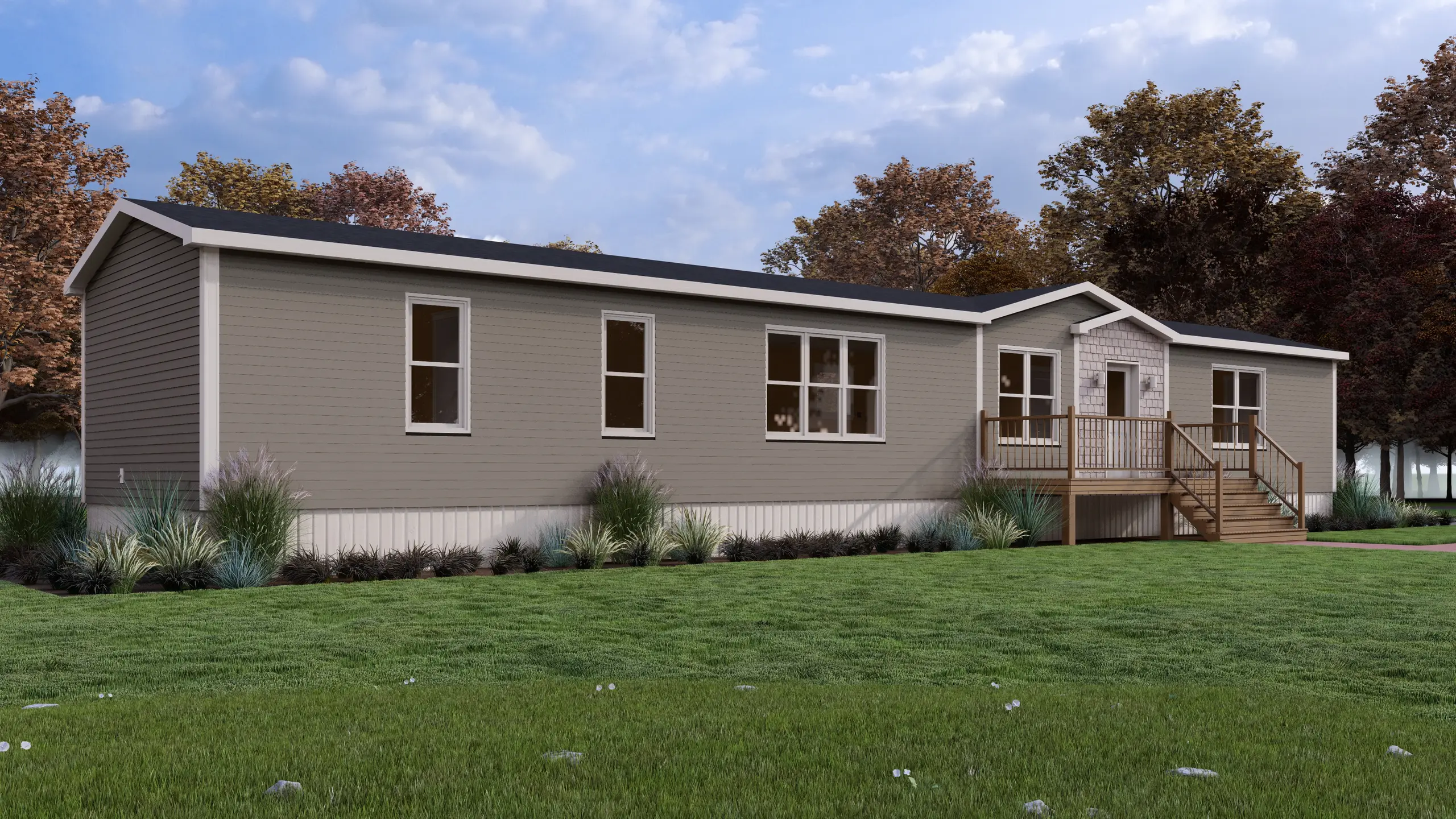 Front angled view of a contemporary mini home featuring taupe siding, a central entry porch, decorative shingle accent, and landscaped foundation beds. 