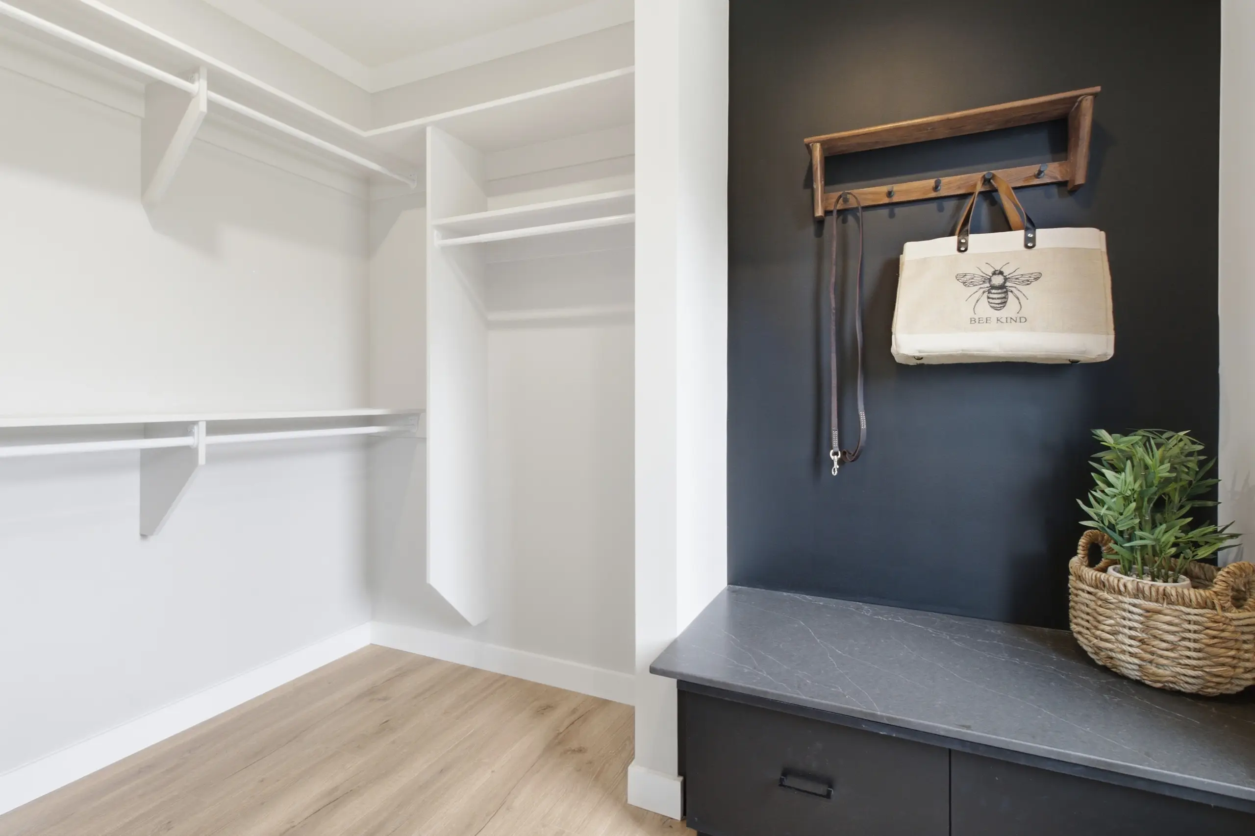 Functional walk-in closet with built-in shelving, hanging space, and an adjacent mudroom bench with storage and coat hooks. 