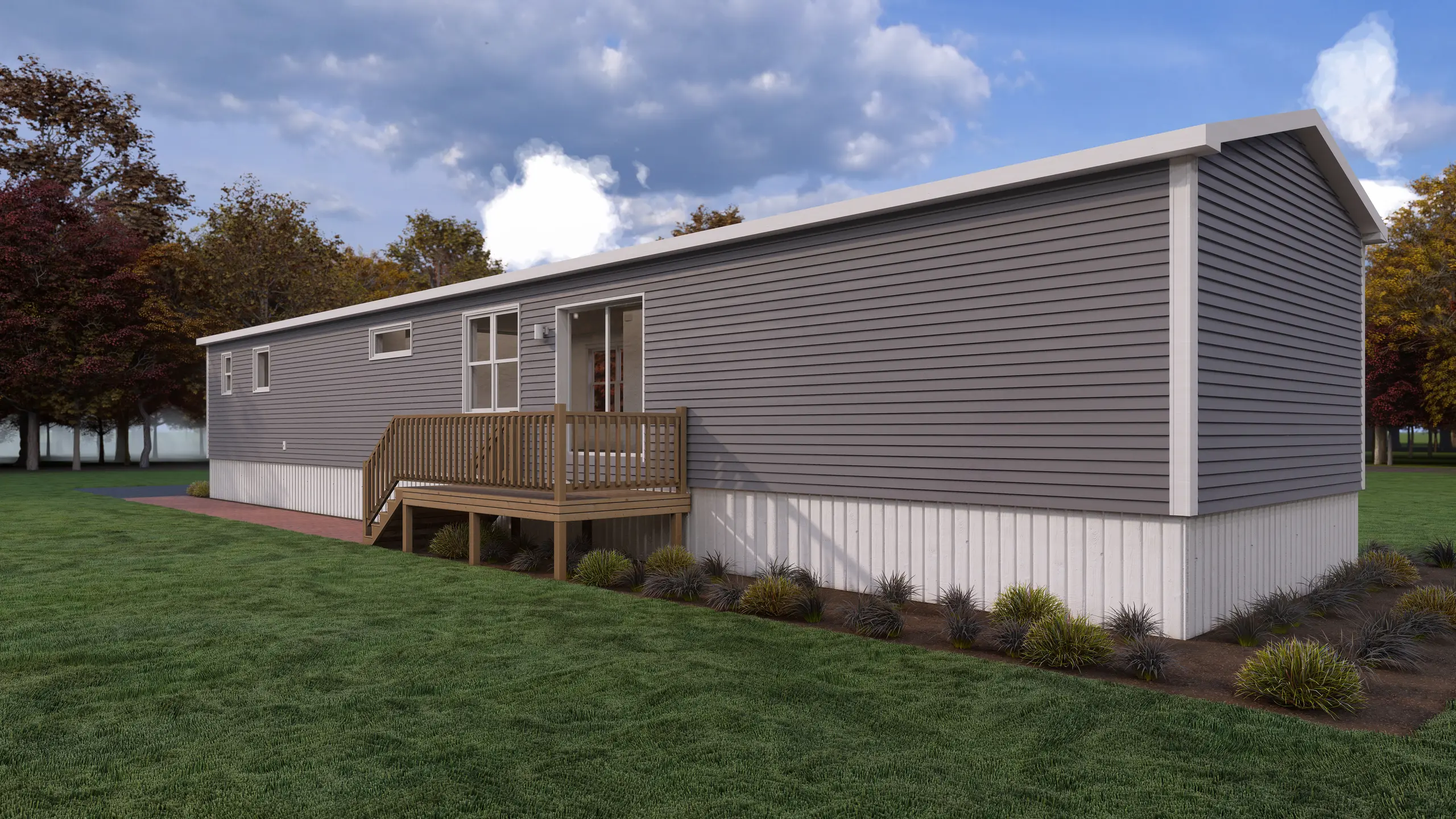 Rear angled view of a contemporary mini home featuring grey horizontal siding, a raised wood deck, rear entry door, and landscaped garden beds. 