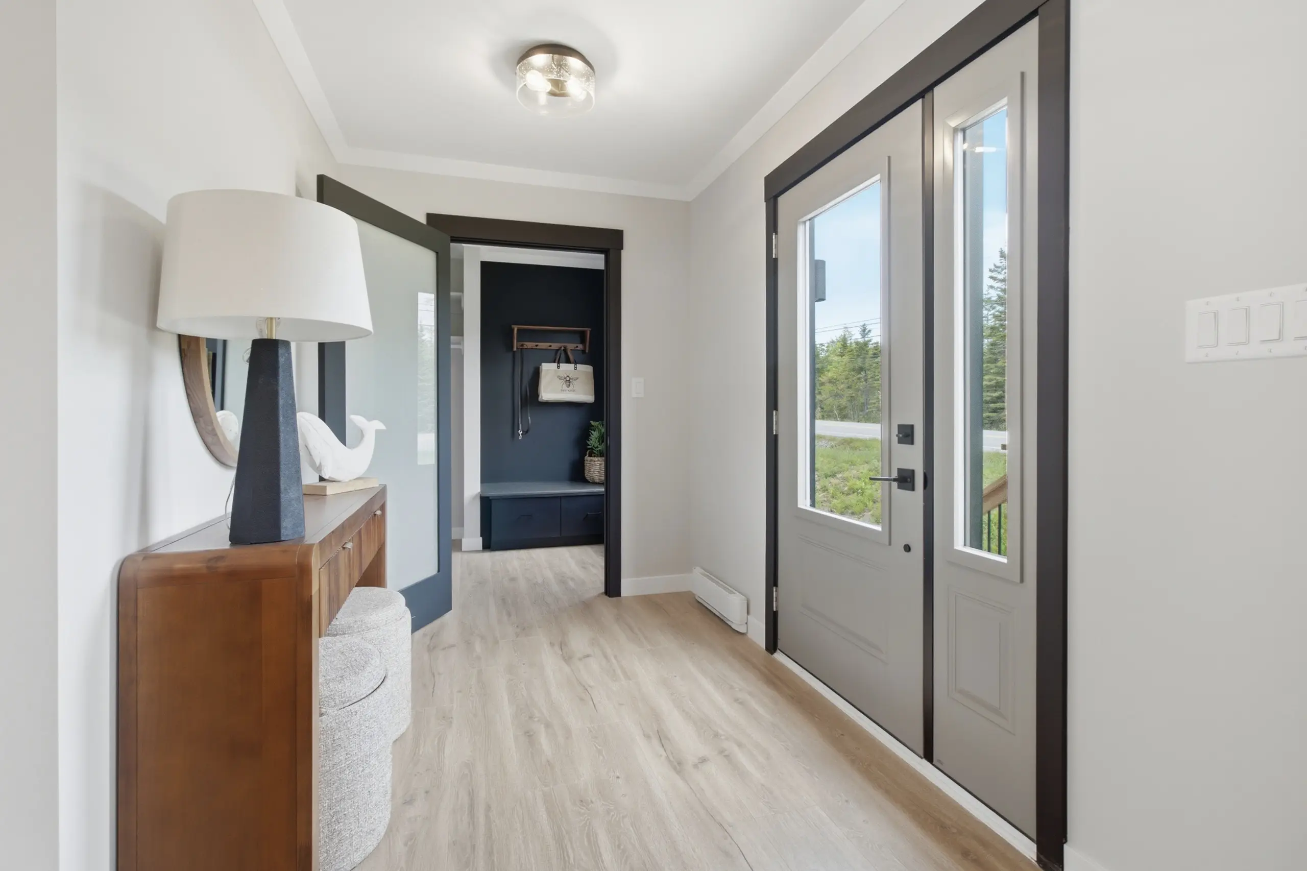 Bright front entry featuring a modern door with sidelights, light wood flooring, contemporary furnishings, and built-in storage just beyond the foyer. 