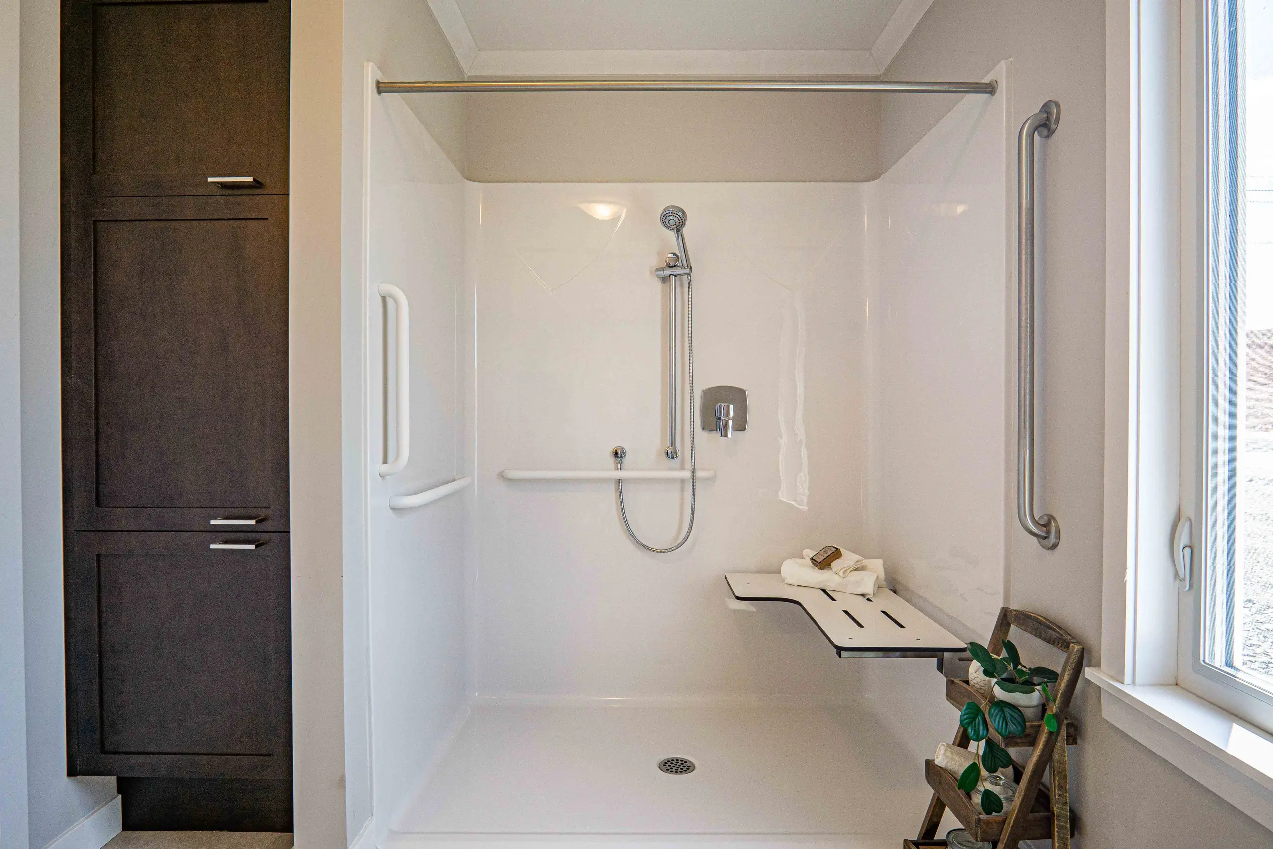 Walk-in accessible shower with built-in seating, grab bars, handheld showerhead, and low-threshold entry. 