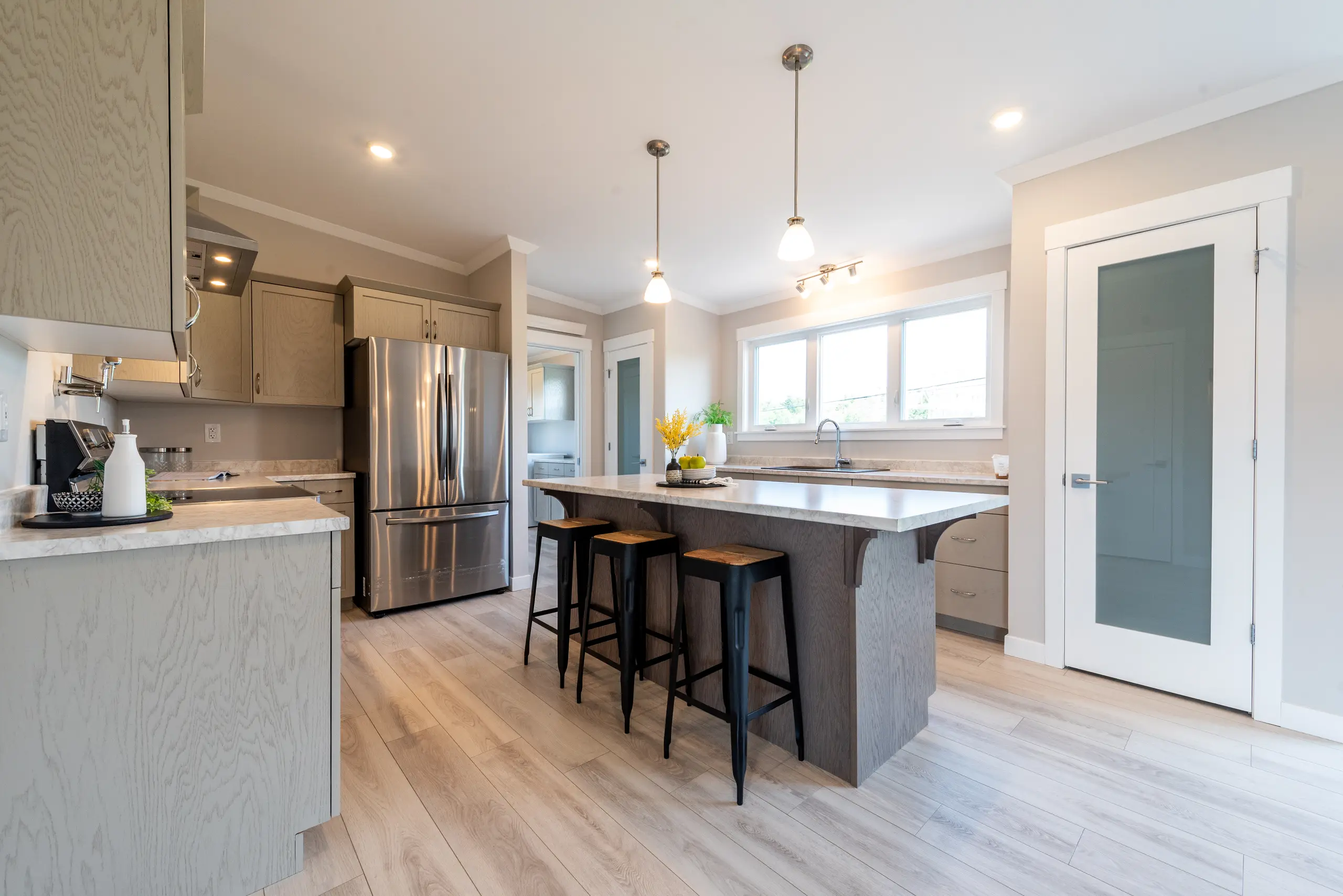 Contemporary kitchen featuring a large island with seating, stainless steel appliances, and ample cabinet storage.