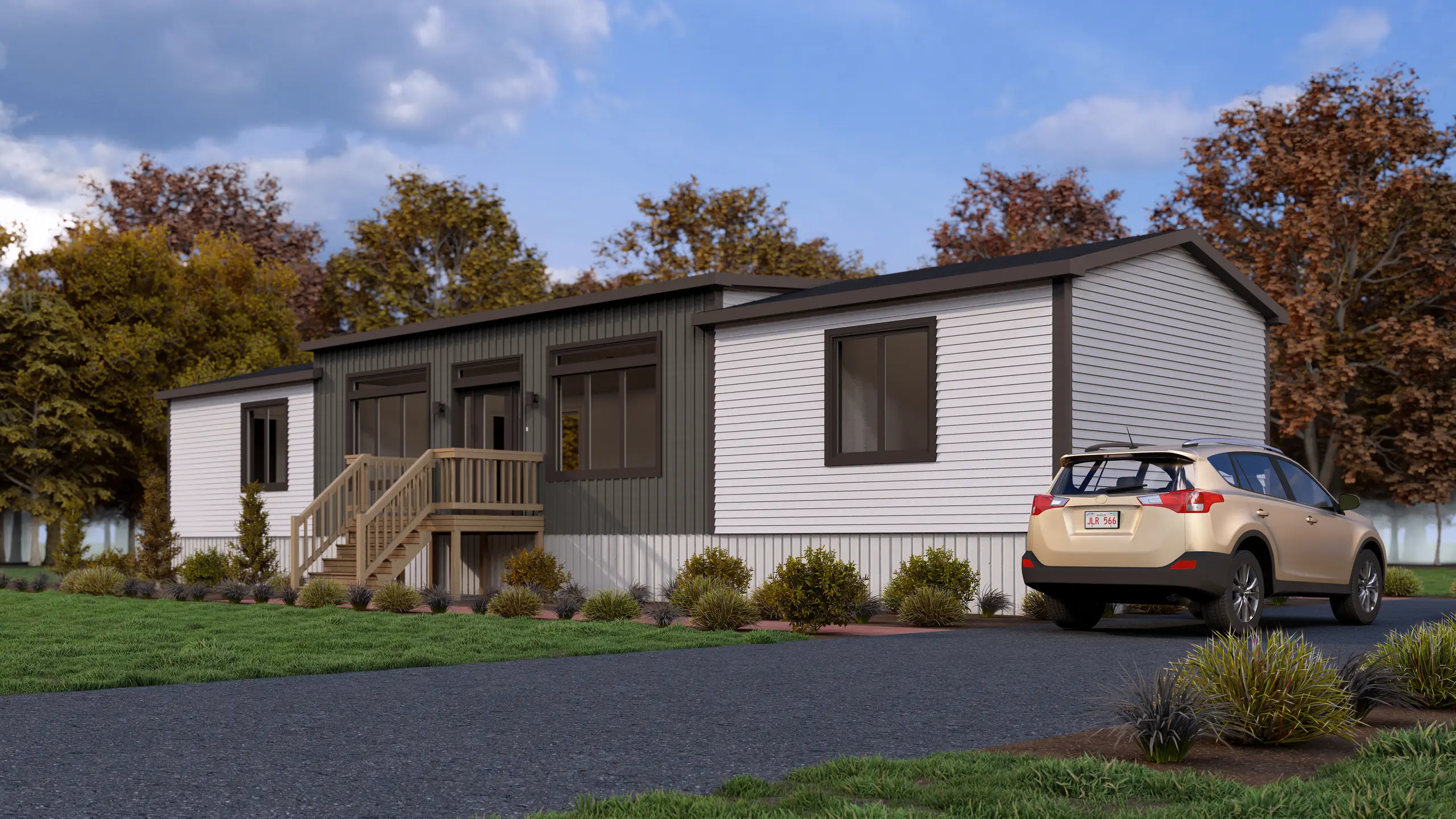 Front corner view of a modern mini home with contrasting exterior finishes, a raised entry deck, paved driveway, and surrounding greenery.