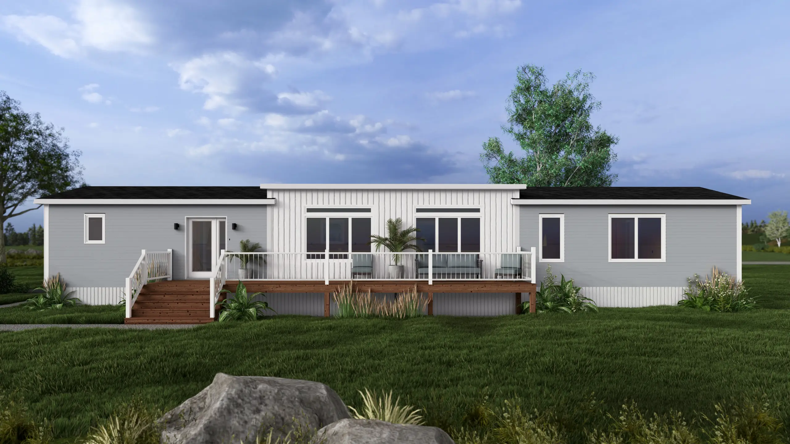 Front elevation of a modern coastal mini home with a full-width raised deck, large picture windows, light grey siding, and landscaped garden beds. 