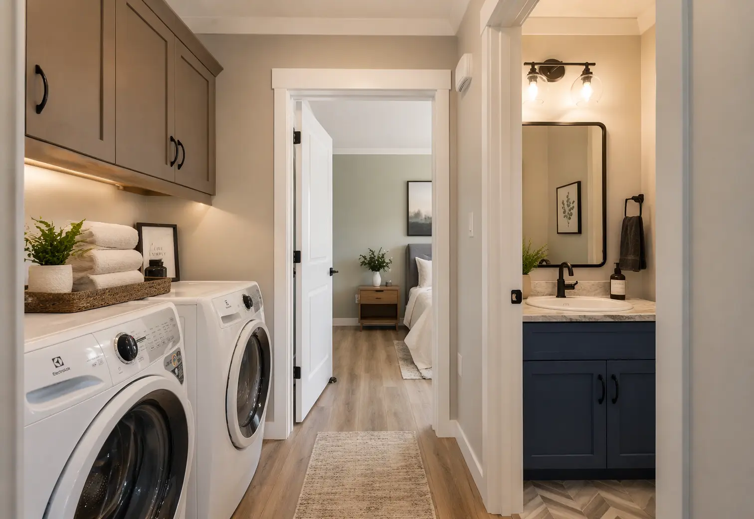 Functional laundry area with upper storage cabinets, front-load washer and dryer, and a nearby bathroom vanity with a marble-look countertop. 