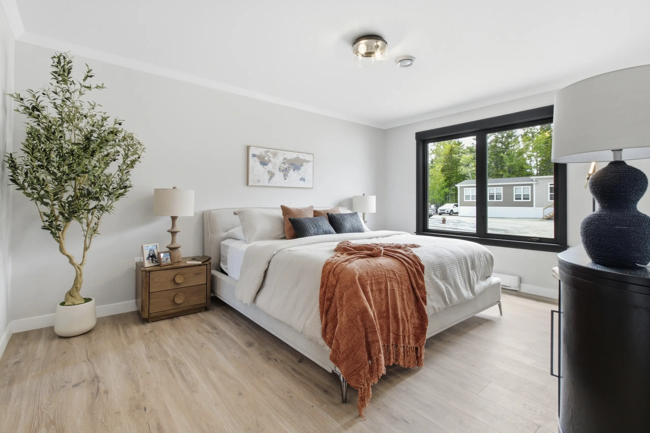 Spacious primary bedroom with a large upholstered bed, oversized window, stylish nightstands, and soft neutral finishes. 