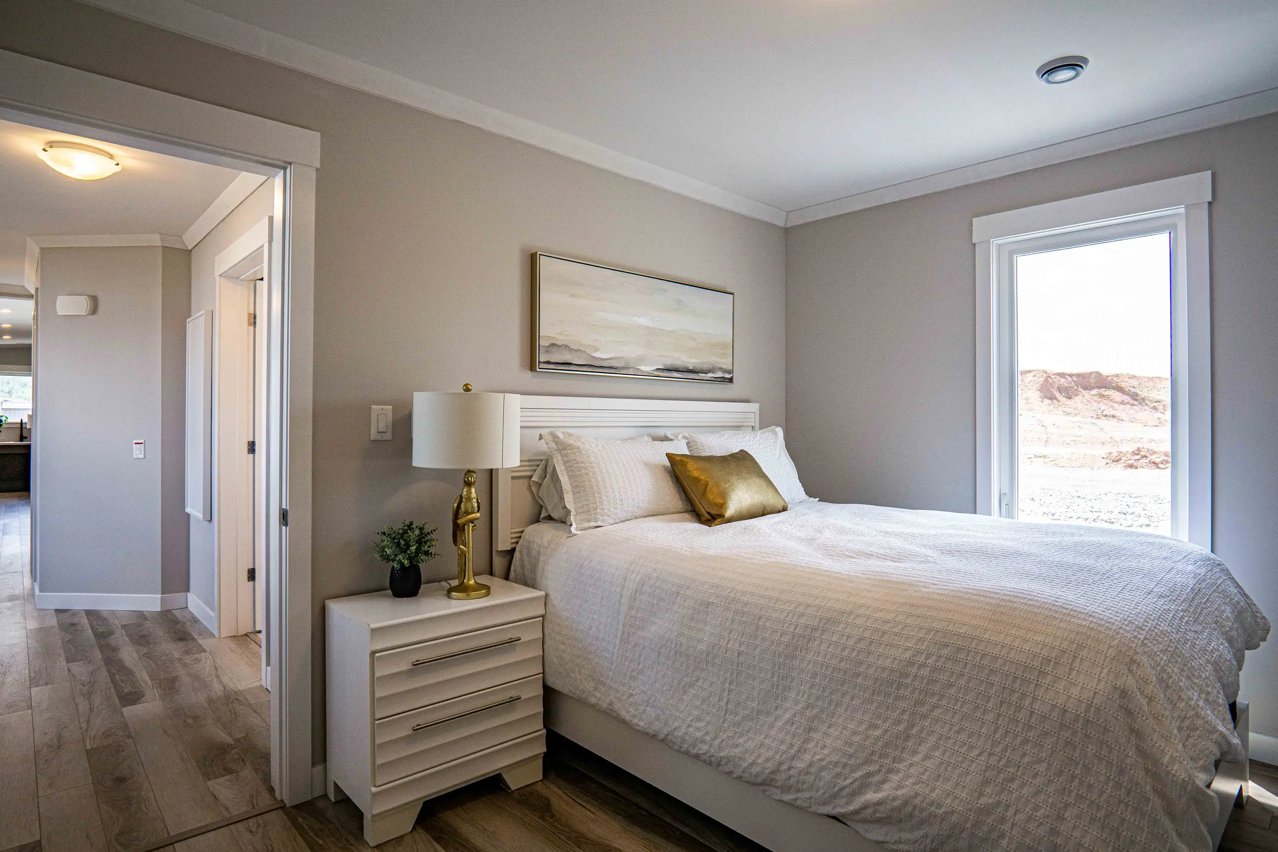 Comfortable primary bedroom with large window, neutral finishes, modern furnishings, and direct access to the main living areas. 