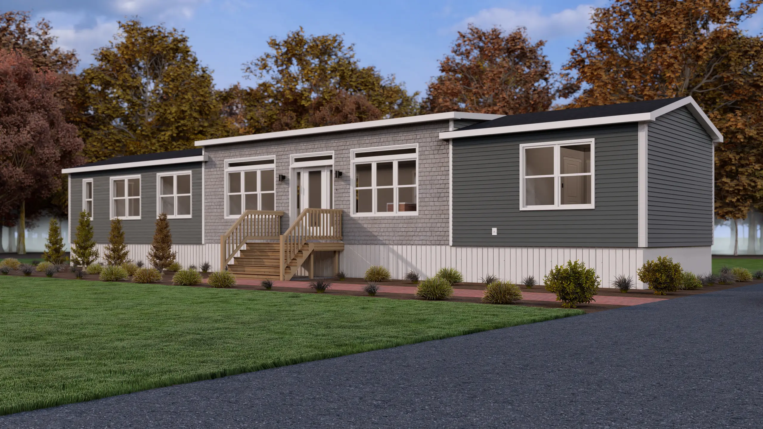 Front corner view of a mini home with contrasting blue-grey siding, cedar shake detailing, large windows, and landscaped gardens along a paved walkway. 