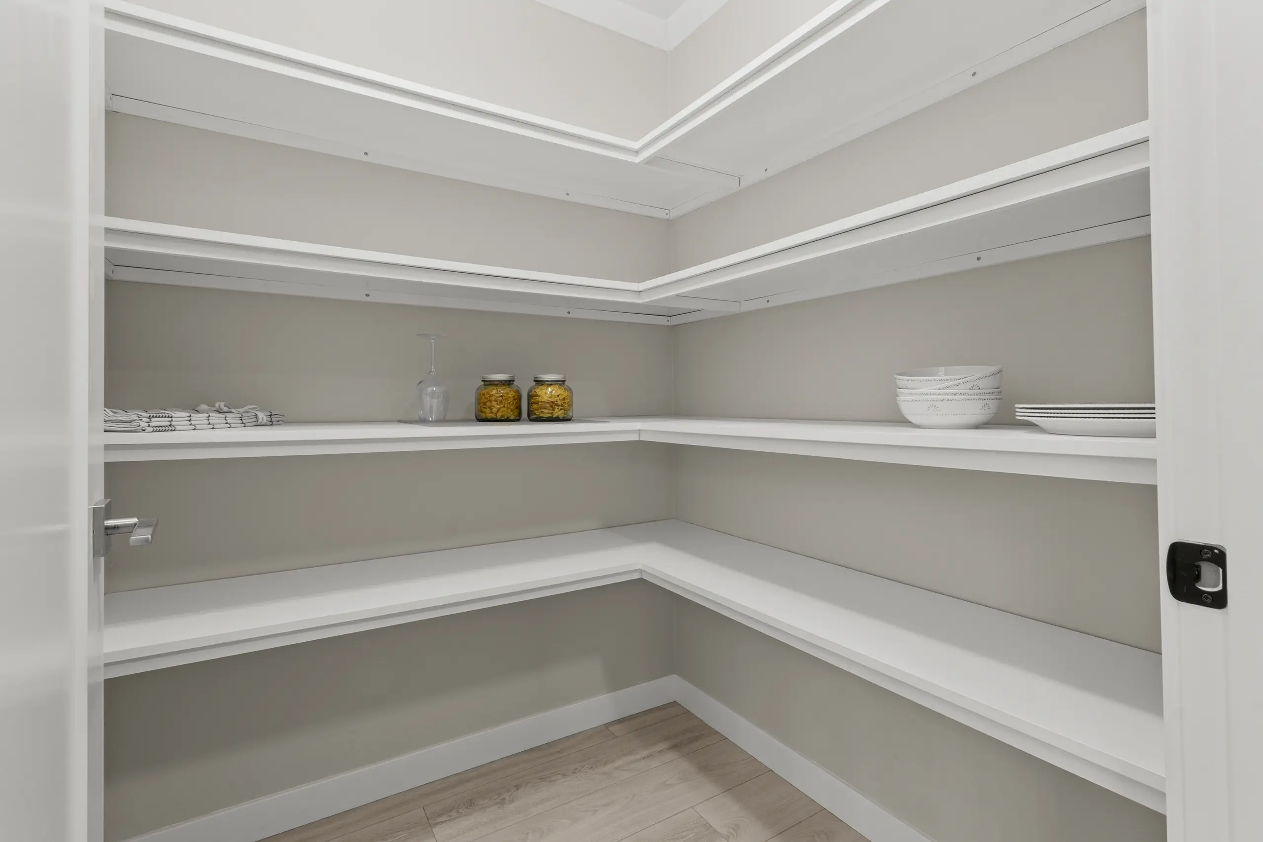 Spacious walk-in pantry with wraparound shelving, ample storage space, and organized kitchen essentials. 