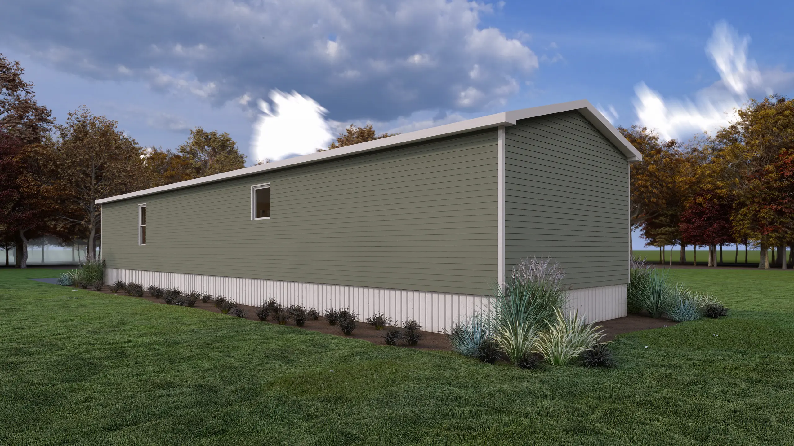 Side view of a modern mini home with sage green siding, white skirting, decorative grasses, and mature trees in the background. 