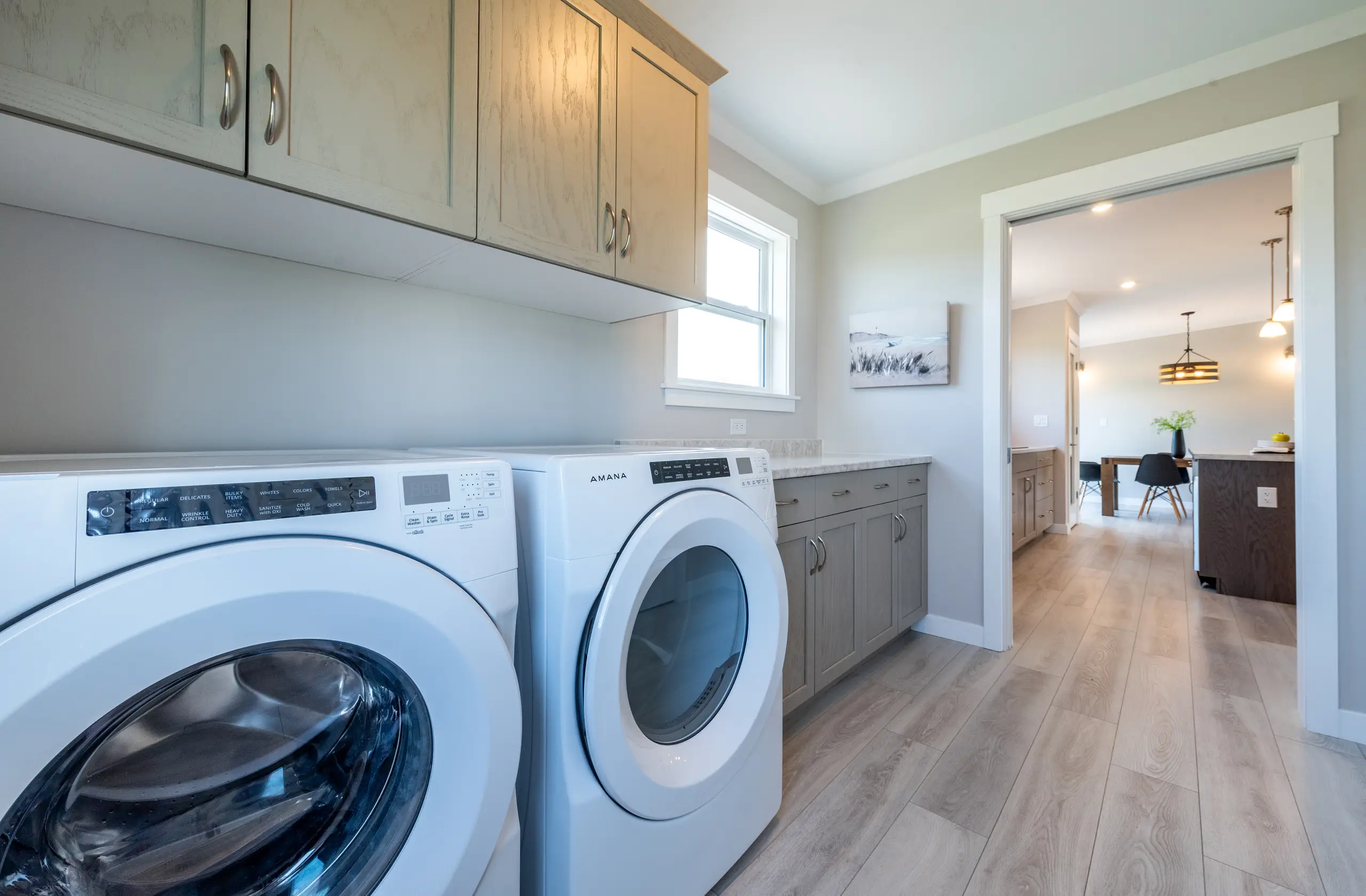Functional laundry room with side-by-side washer and dryer, built-in cabinetry, and countertop workspace.