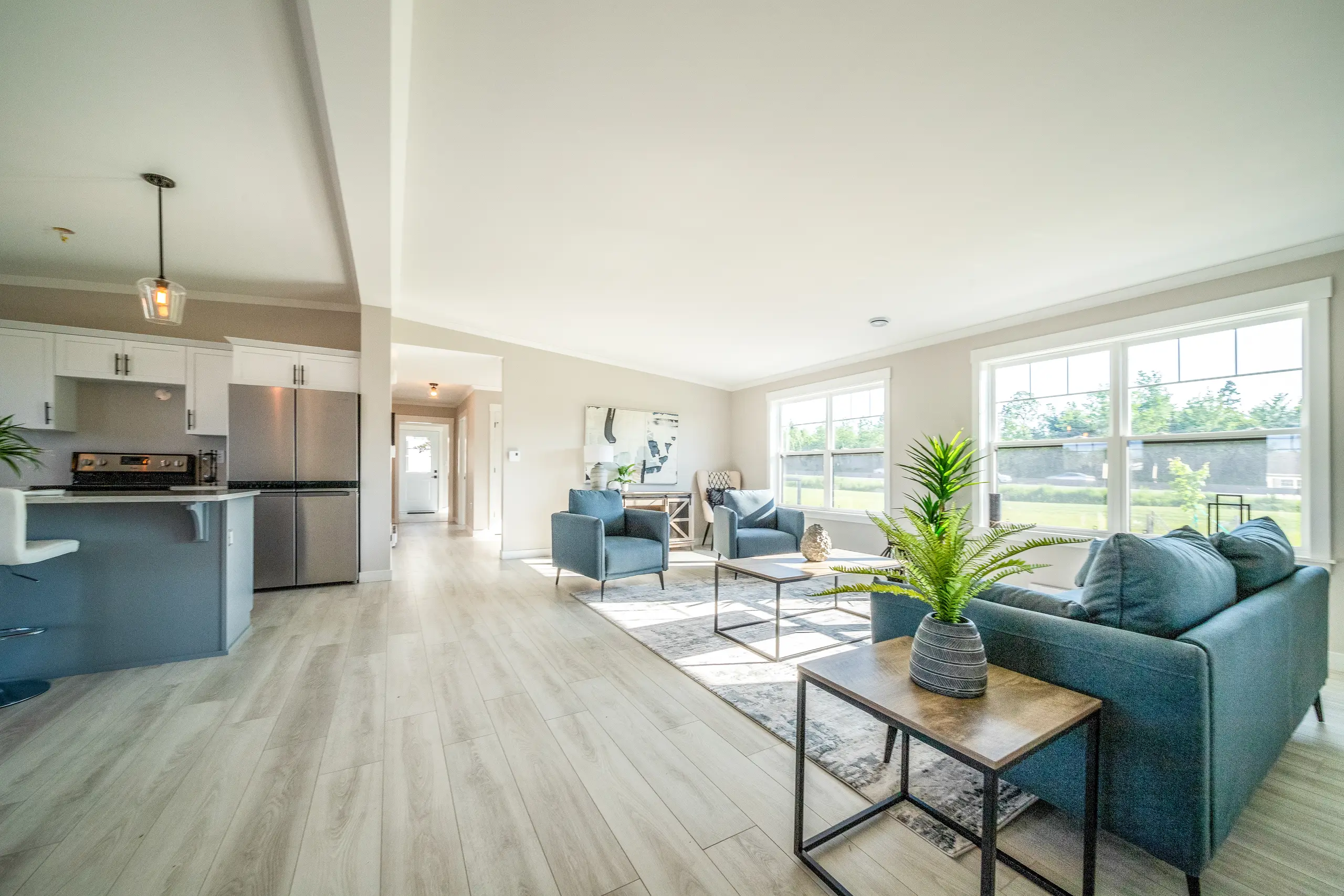 Bright open-concept living room and kitchen featuring large windows, modern furnishings, and abundant natural light. 