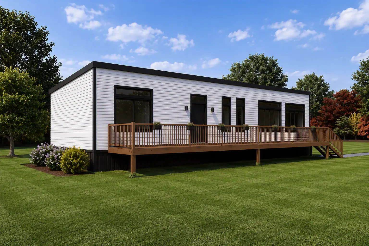 Modern modular home with an extended wood deck, black-framed windows, sliding patio doors, white siding, and landscaped surroundings, set within a private, park-like setting. 